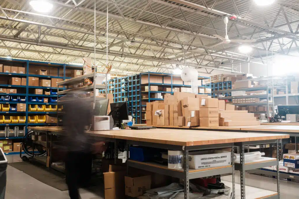 Blurry photo of a person moving inside a warehouse space with boxes on a table